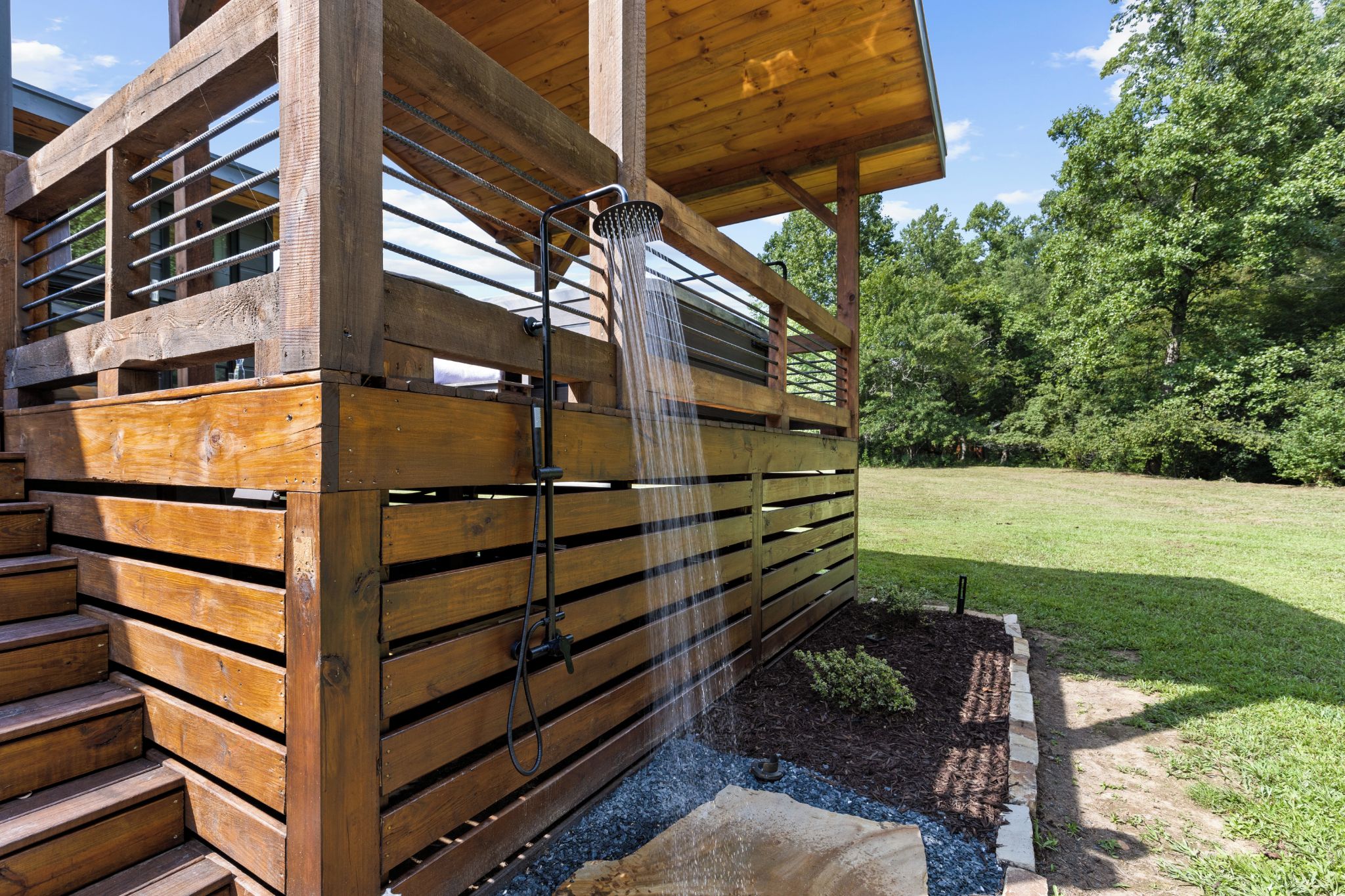 Una cabaña de madera con terraza de madera y una cascada.