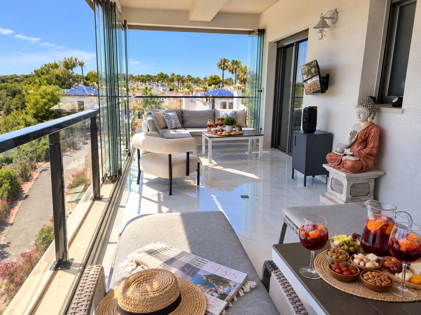 A balcony with a sofa, table, and Buddha statue, overlooking a resort area.