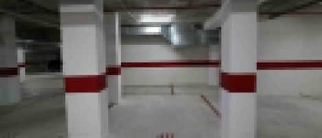 Un pasillo con pilares blancos y detalles en rojo, que conduce a una puerta.
