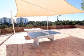 An outdoor table tennis setup with a canopy, surrounded by a brick patio, and a fence in the background. - 3 Bedroom, 2 bathroom Greenhills apartment, indoor pool, gym, spa childrens park (Los Dolses)