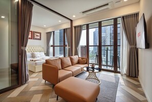 Habitació d'hotel moderna amb un sofà, un otomà i una taula petita amb objectes decoratius.
