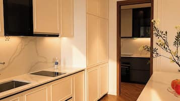 Una cocina moderna con muebles blancos, encimera de mármol y suelo de madera.