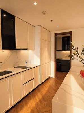Una cocina moderna con muebles blancos, encimera de mármol y suelo de madera.