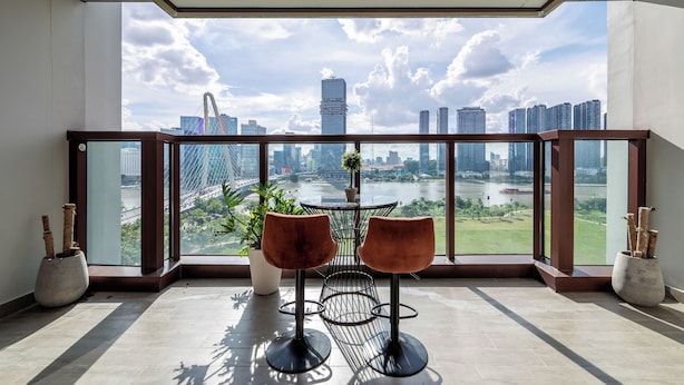 Un balcón con dos sillas y vistas a un paisaje urbano y un río.