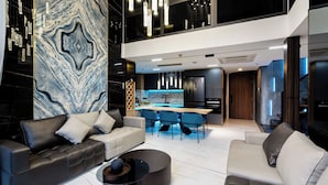 Una sala de estar moderna con un conjunto de sofás, una mesa de centro y una zona de cocina con una mesa de comedor.