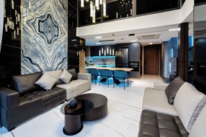A modern living room with a sofa set, a coffee table, and a dining area with chairs. - Metropole Riverside Luxury Apartment (Thu Duc)