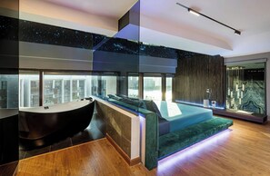 Ein modernes Badezimmer mit einer großen Badewanne, einem Waschtisch und einer Sitzecke mit Blick auf die Stadt.