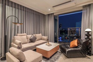 A modern living room with a sofa, a coffee table, and a leather chair. - Metropole Riverside Luxury Apartment (Thu Duc)
