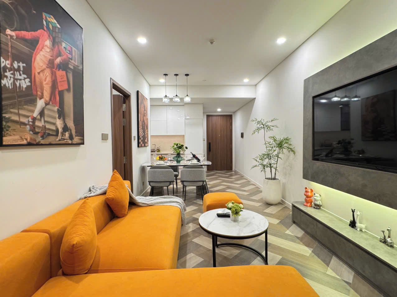 Una sala moderna con sofá, comedor y cocina al fondo.
