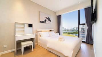 Habitación de hotel con cama, escritorio, silla, ventana grande con vista a la ciudad y un cuadro en la pared.