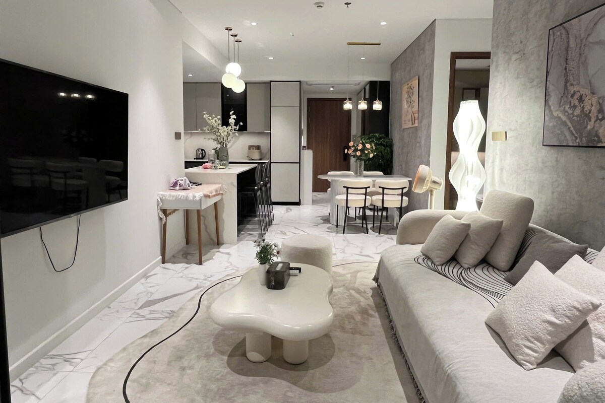 A modern living room with a sofa, coffee table, and a flat-screen TV mounted on the wall.