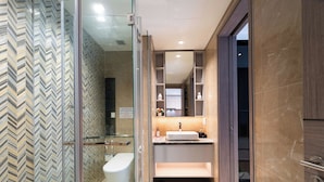 Un baño moderno con cabina de ducha de vidrio, inodoro, lavabo con tocador y espejo sobre el lavabo.