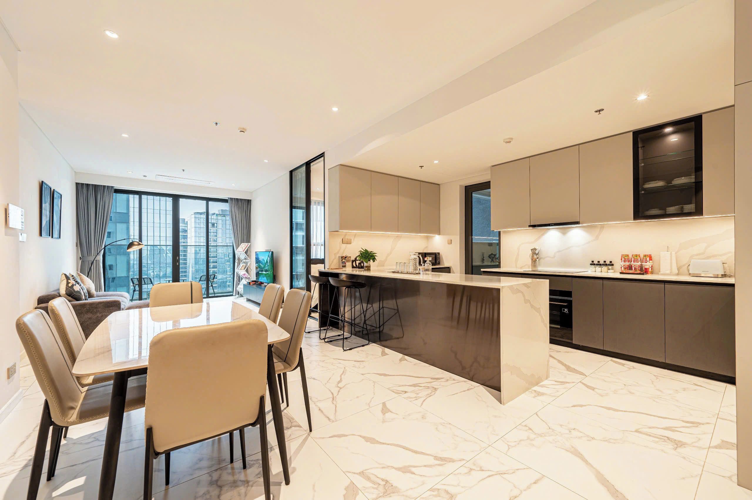 A modern kitchen with a marble countertop, a dining area with a table and chairs, and a view of the city through large windows.