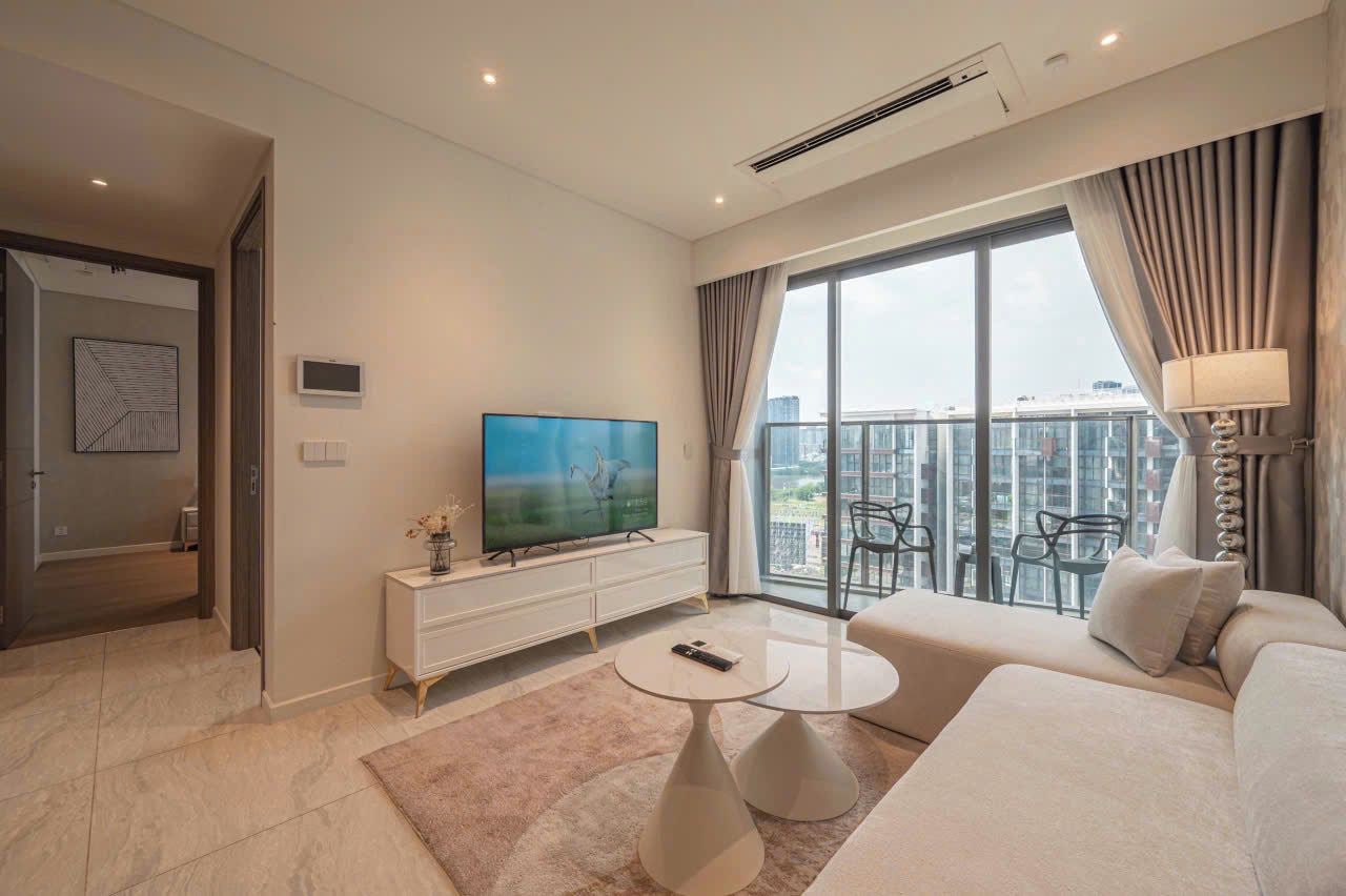 Un salon moderne doté d’un téléviseur à écran plat, d’un canapé, d’une table basse et d’un balcon offrant une vue sur la ville.