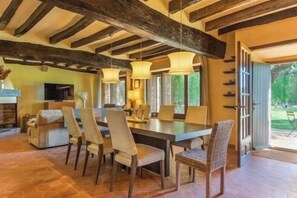 A dining area with a large table, chairs, and hanging lights.