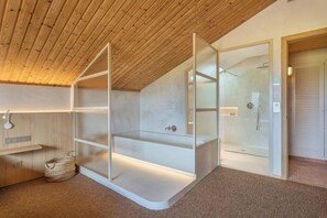 A modern bathroom with a wooden ceiling, glass shower enclosure, and built-in shelves.
