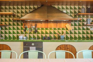 A kitchen with a checkered backsplash, hanging utensils, a coffee maker, and a stove.