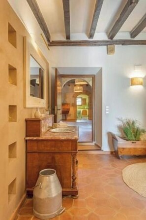 A hallway with a wooden bench, a mirror, and a metal container on the floor. - Historic Catalan farmhouse with pool near Girona (Cornellà del Terri)