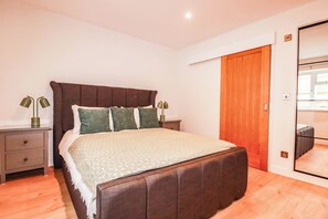 Ein Schlafzimmer mit einem Bett, Nachttischen, einem Kleiderschrank und einem Spiegel.