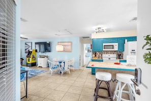 A modern kitchen with teal cabinets, a white microwave, and a coffee machine. - Beachside Bliss. 2nd row Windy Hill. Outdoor pool. Perfect location! (North Myrtle Beach)