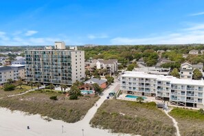 A coastal hotel with multiple floors, a swimming pool, and a beach area. - Beachside Bliss. 2nd row Windy Hill. Outdoor pool. Perfect location! (North Myrtle Beach)