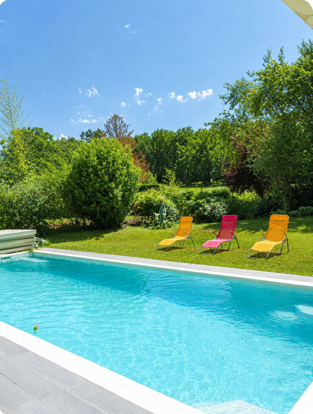 Ein Schwimmbecken mit drei Liegestühlen und einer Holzterrasse.