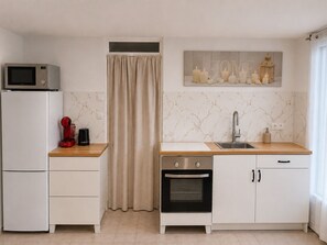 A compact kitchen with a microwave, coffee maker, oven, and a sink.