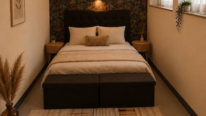 Una camera da letto con un letto grande, una lampada a parete, un tappeto decorato e una finestra con tende.