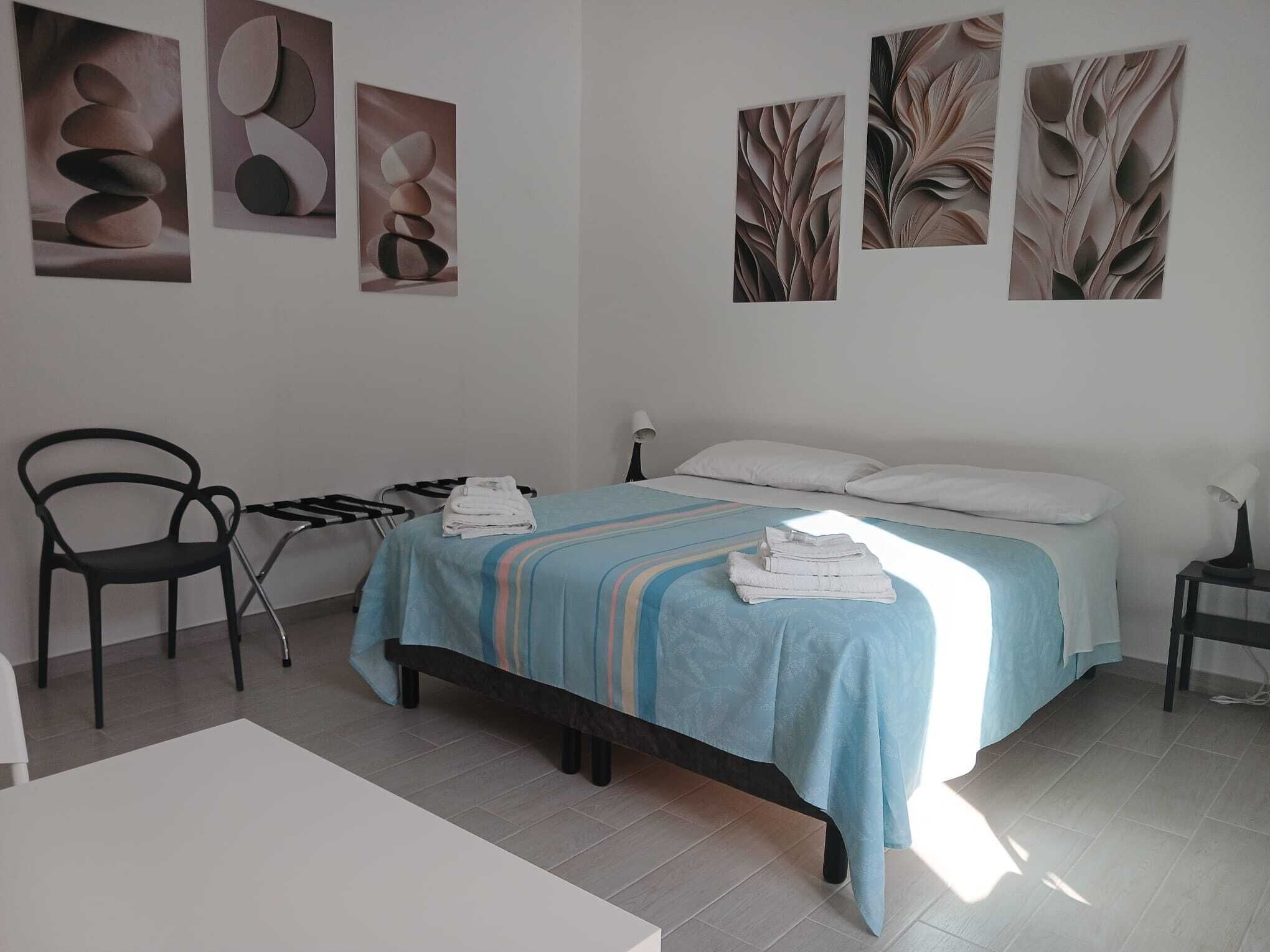 Una habitación de hotel con una cama, una silla y obras de arte en las paredes.