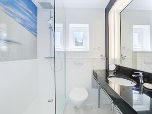 Ein modernes Badezimmer mit einer Duschkabine aus Glas, einer weißen Toilette und einer schwarzen Waschtischplatte mit Waschbecken.