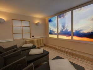 Ein Spa-Raum mit großem Fenster, Heizkörper und mehreren Massagetischen.