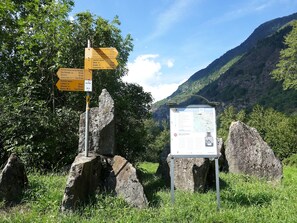 A mountain trail signpost with multiple directional signs and a map. - Apartment Dolfo by Interhome (Ludiano)