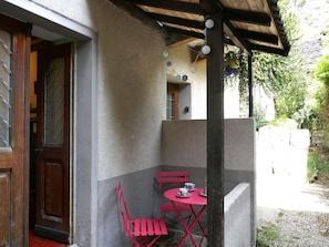 A patio area with a table and chairs, a door, and a view of greenery. - Apartment Dolfo by Interhome (Ludiano)