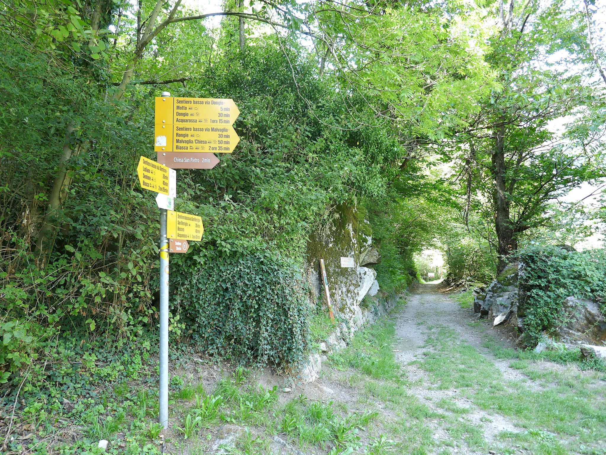 A directional signpost with multiple yellow signs indicating distances and directions to various locations.