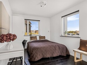 Ein modernes Schlafzimmer mit einem Bett, einem Schreibtisch und einem Fenster.
