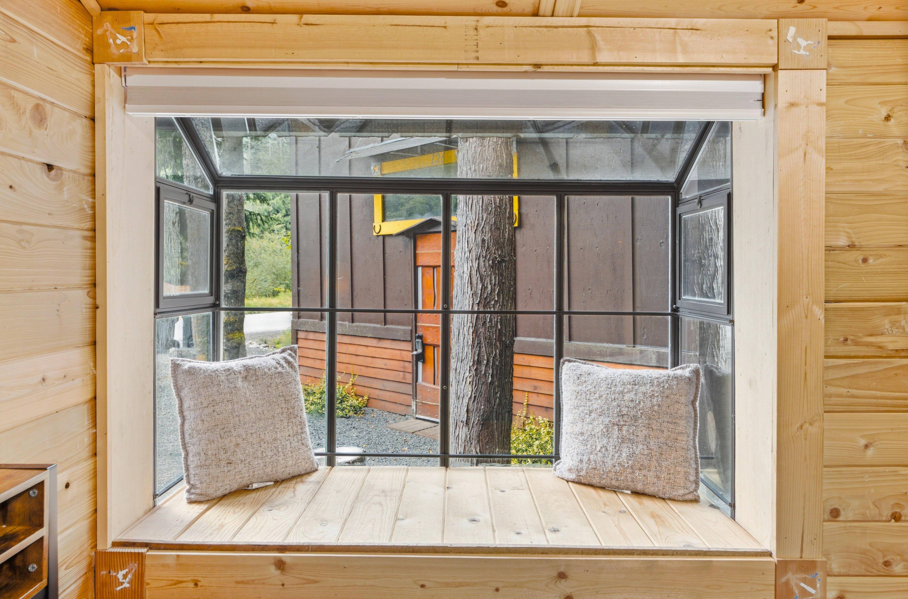 Una habitación con un ventanal que ofrece vista a una terraza de madera y un árbol.
