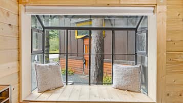 Una habitación con un ventanal que ofrece vista a una terraza de madera y un árbol.