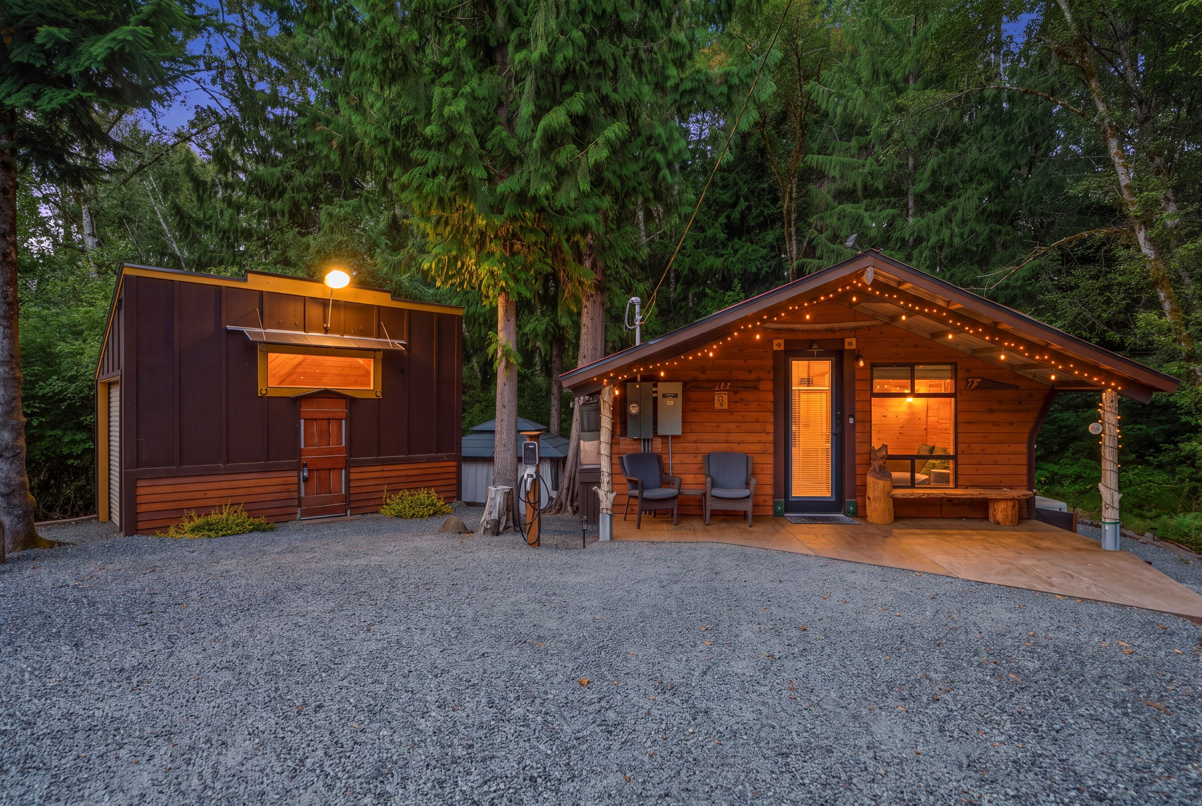 A cabin with a covered outdoor seating area and a separate building with a grill.
