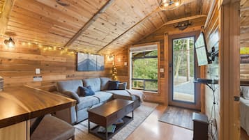 Interior acogedor de una cabaña con techo de madera, un sofá, una mesa de centro y una mesa de comedor.