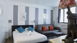 Une chambre d’hôtel avec un lit, un canapé, une petite table et une statue.