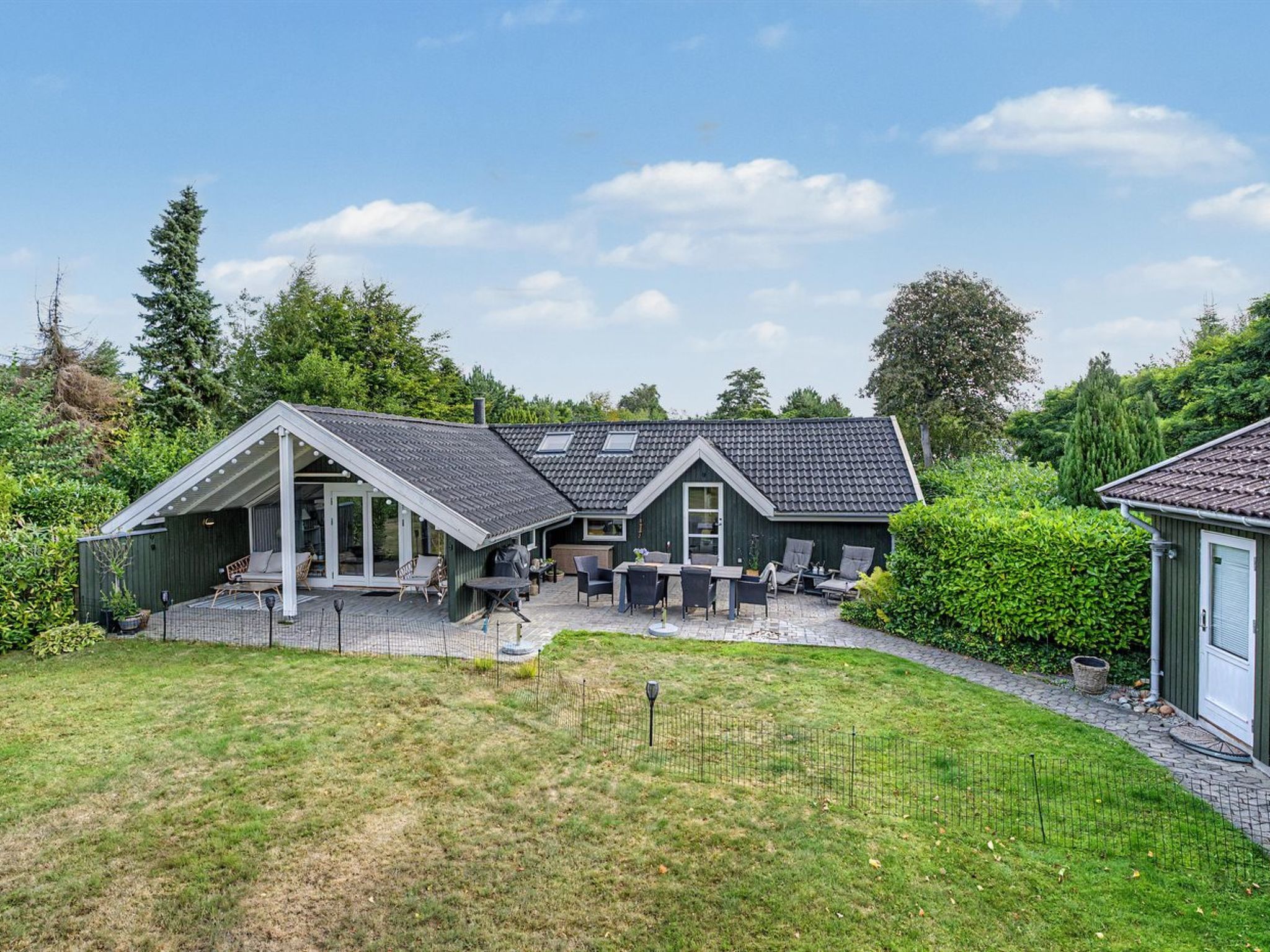 Een huis met een overdekte patio, een omheinde achtertuin en een gazon.