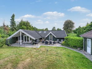 A house with a covered patio, a fenced backyard, and a green lawn. - "Aleksis" - 900m from the sea by Interhome (Væggerløse)