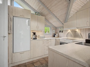 A modern kitchen with wooden cabinets, a built-in oven, and a large island with a sink. - "Aleksis" - 900m from the sea by Interhome (Væggerløse)
