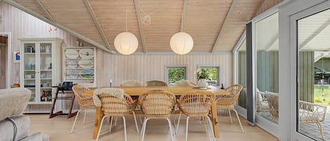 A dining area with a wooden table, wicker chairs, and a glass door leading outside.