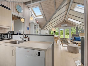 Een moderne keuken met een Bosch vaatwasser, een eethoek met een tafel en stoelen, en een uitzicht op de omgeving door grote ramen.