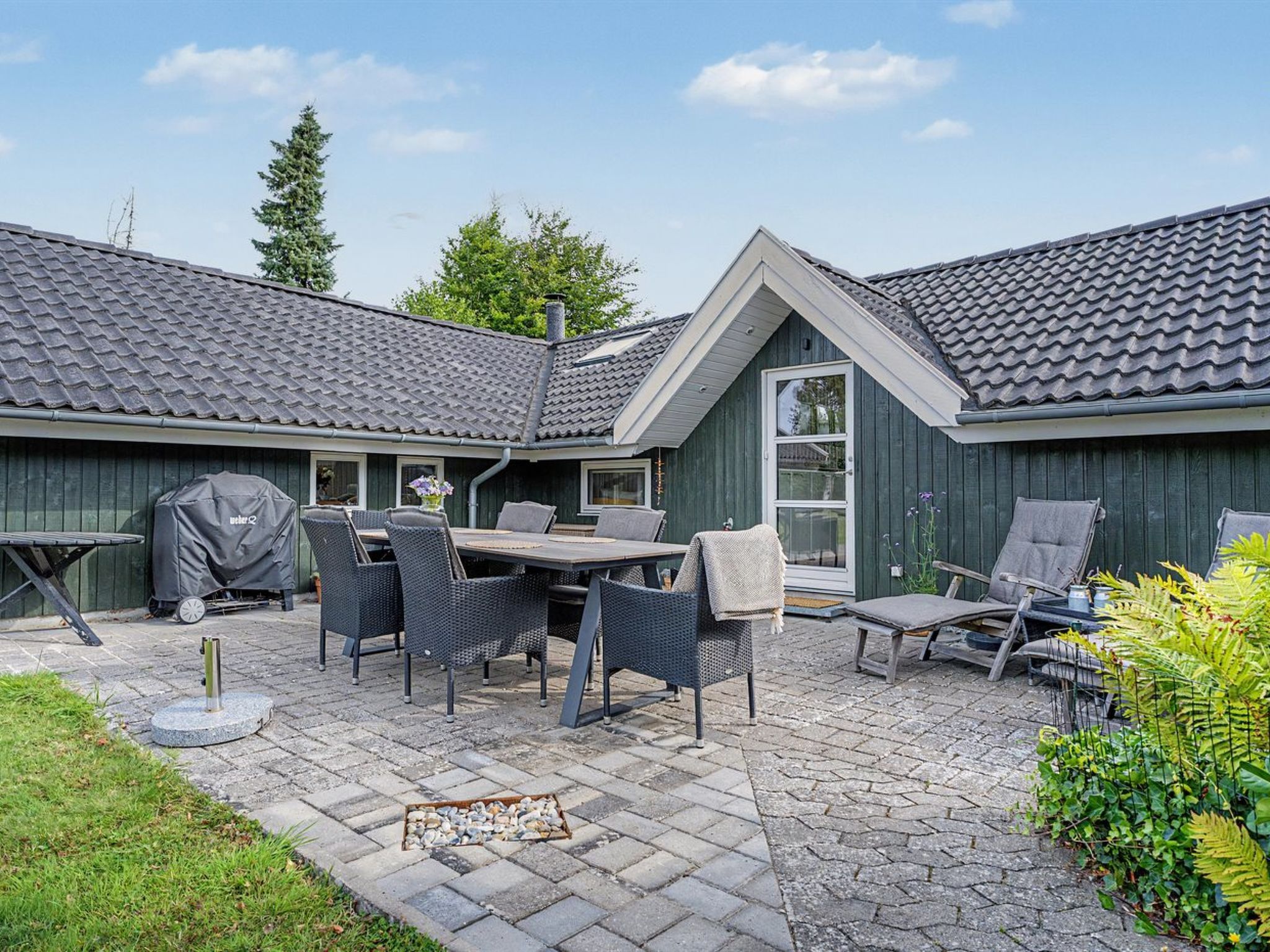 A patio with a table and chairs, a barbecue grill, and a covered area.