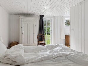 A bedroom with a bed, a chair, a wardrobe, and a door leading to a garden. - "Brynja" - 2.5km from the sea by Interhome (Højby)