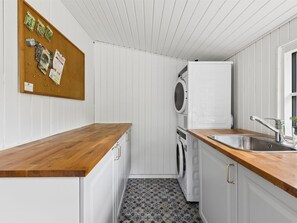 Une cuisine compacte avec des plans de travail en bois, un lave-linge et un petit évier.