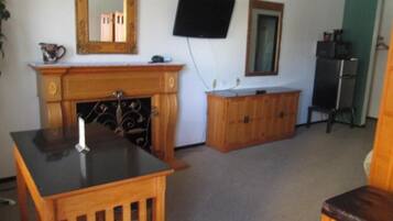 A room with a fireplace, a television mounted on the wall, and a cabinet.
