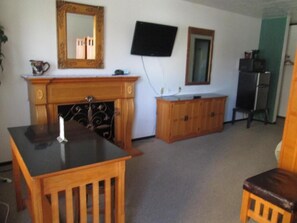 A room with a fireplace, a television mounted on the wall, and a cabinet.